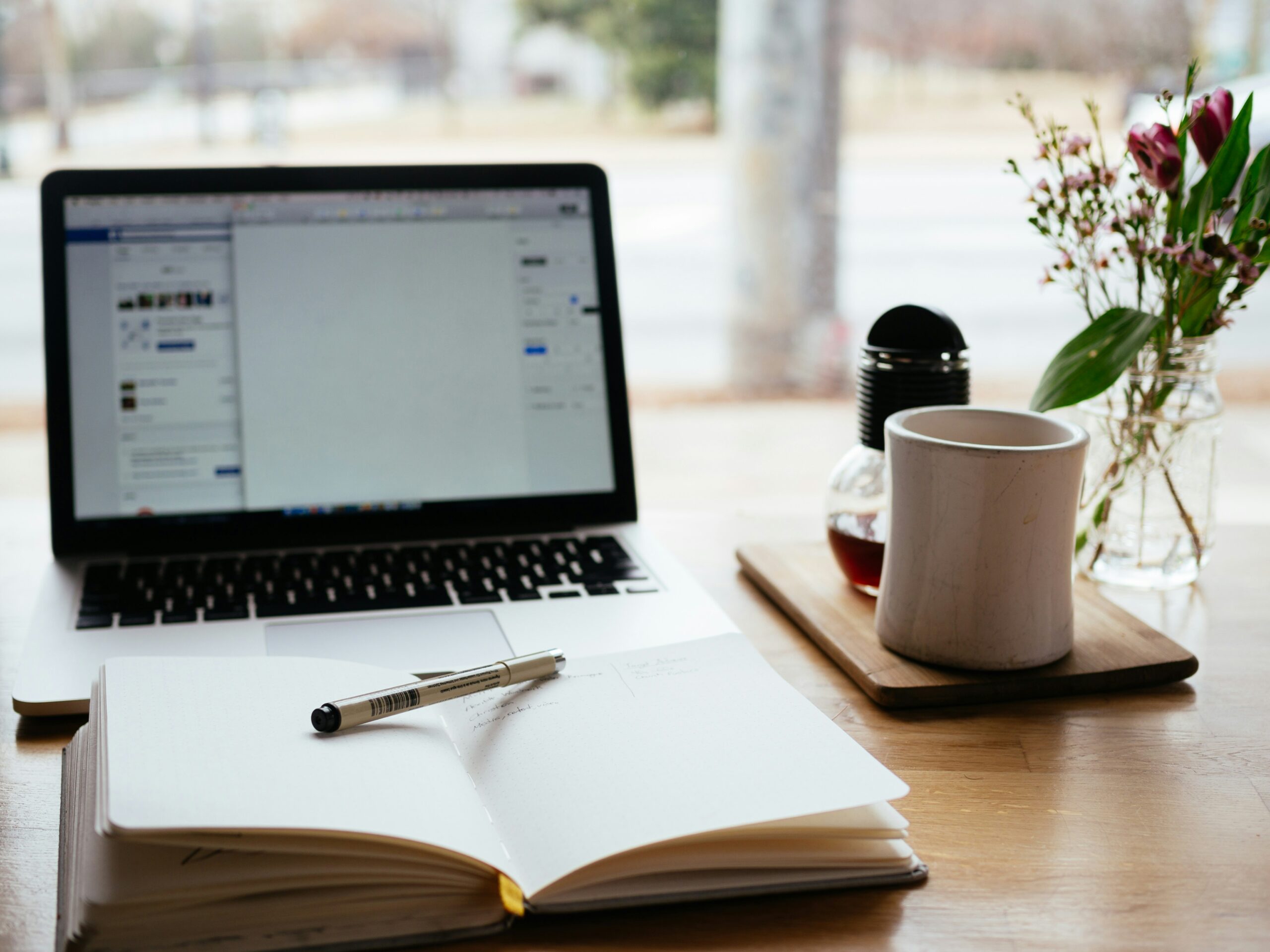 A computer, notebook and a cup of coffee
